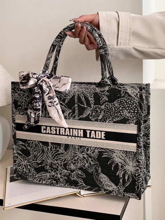 Handbag with black and white pattern and 'Castrainh Tade' branding held by a person.