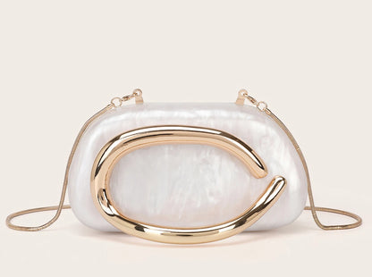 White handbag with gold accents on a beige background