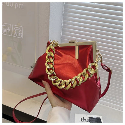 Carauana UNIU Aurora Clutch with gold chain handle held by a hand, indoor setting