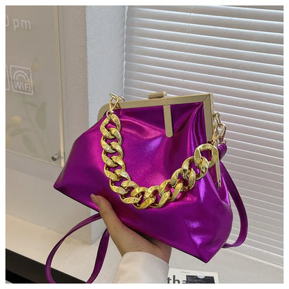 Carauana UNIU Aurora Clutch with gold chain held by a hand in an indoor setting