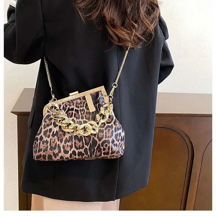 Person wearing a Carauana_UNIU_Leopard_Clutch with gold chain detail