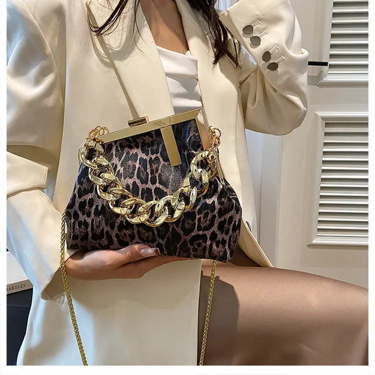 Person holding a Carauana_UNIU_Leopard_Clutch with gold chain detail