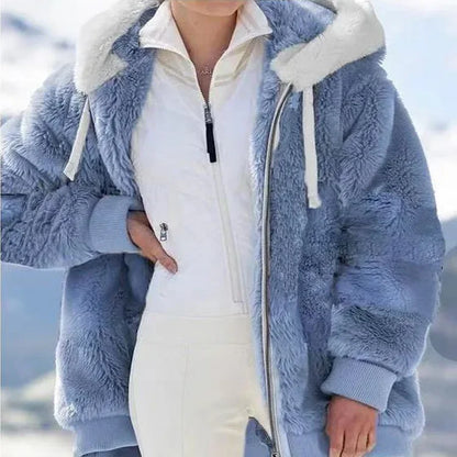 Person wearing a blue fluffy jacket with a white interior against a blurred outdoor background