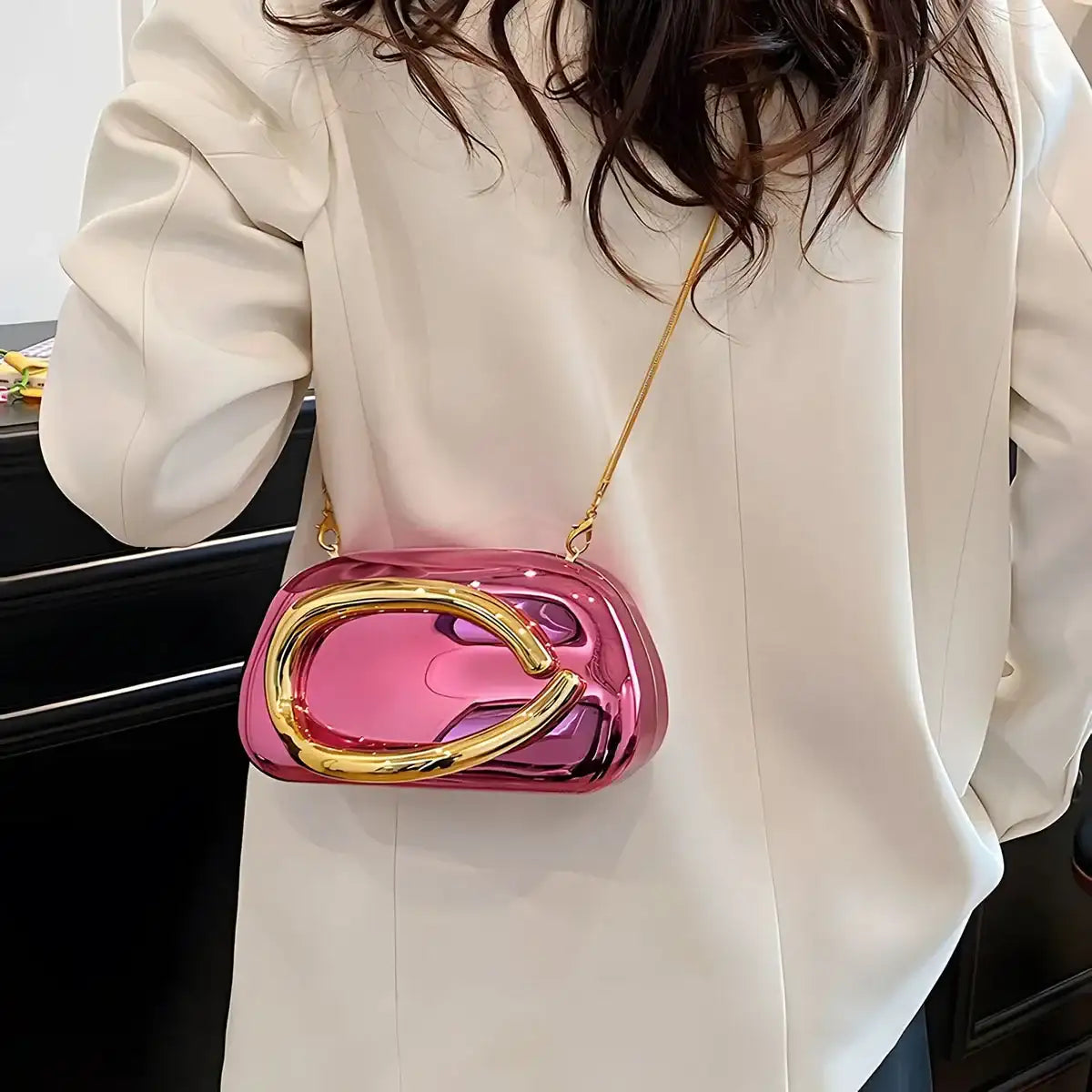 Person wearing a white blouse with a pink and gold Metallic Carauana Festival Clutch Bag 