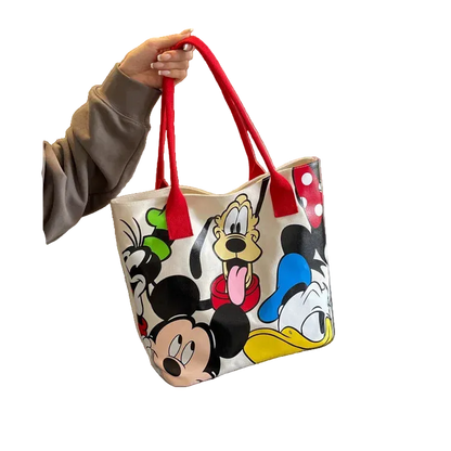 Tote bag with cartoon character designs held by a person, placed on a surface.