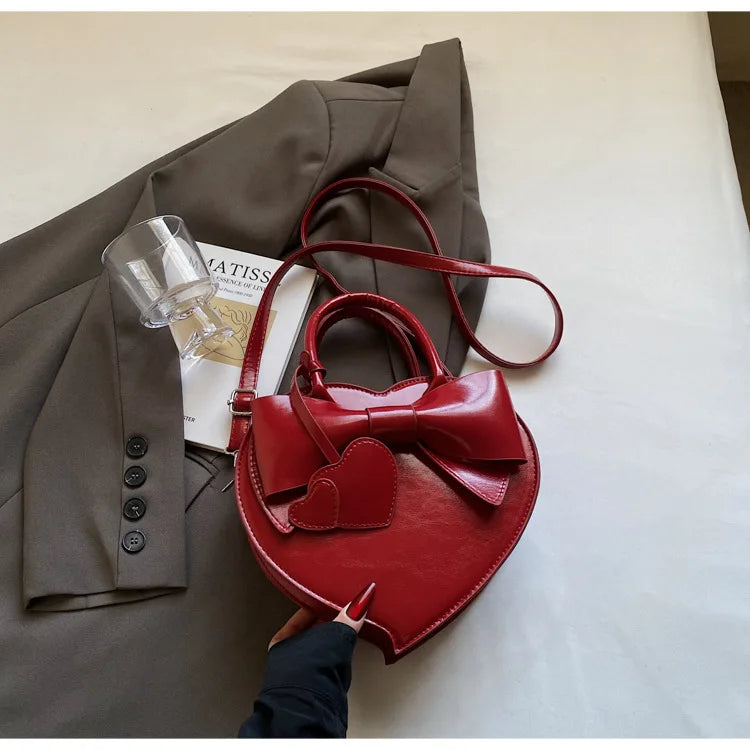 Red carauana-lovely-shoulder-bag-heart with a bow on a surface.
